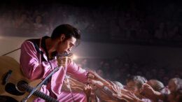 Actor Austin Butler performs as Elvis Presley in a pink suit, singing to an adoring crowd