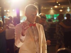 Band leader Tony Farrell conducts his band wearing a white suit with a red bowtie