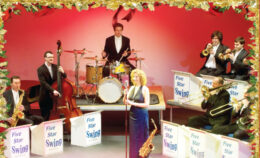 A swing band perform on stage against a red background