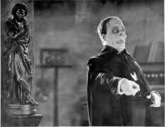 Actor Lou Chaney stands dressed as the grotesque figure, the Phantom of the opera in a black and white image from the 1925 silent film of the same name