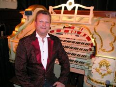 Organist Andrew Nix sits beside his white Wurlitzer organ