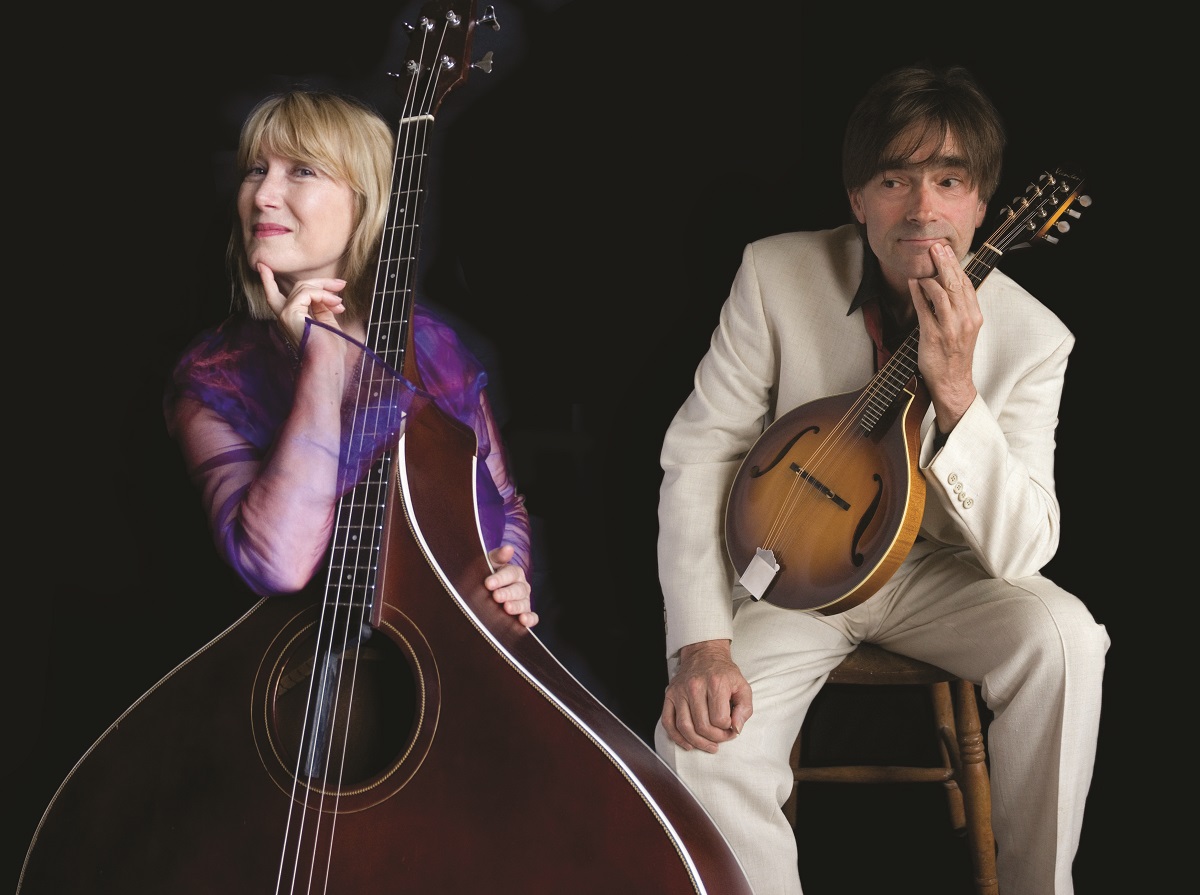 Musicians Hilary James and Simon Mayor pose against a black background with their instruments